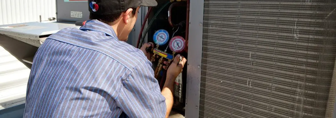 HVAC technician servicing a condenser unit in South St. Paul